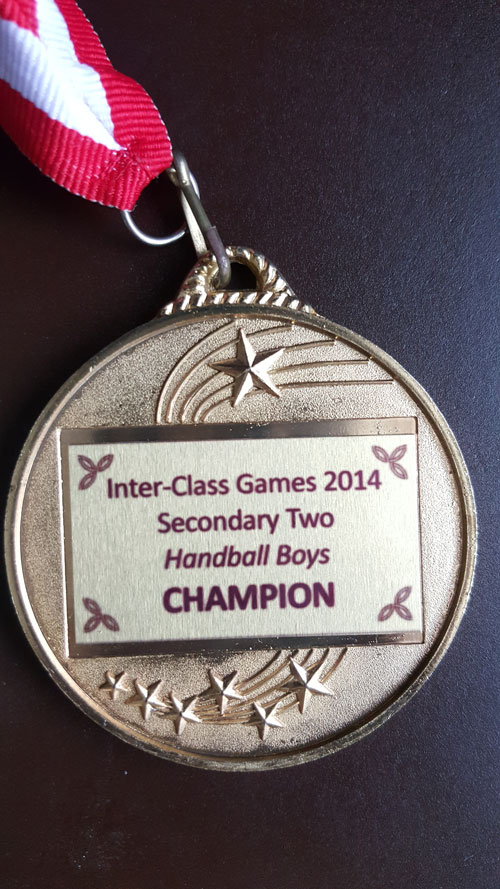 Picture of medal that states 'Inter-Class Games 2014 Secondary Two Handball Boys CHAMPION
